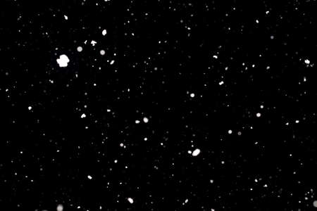Snowstorm texture. Bokeh lights on black background, shot of flying snowflakes in the airの写真素材