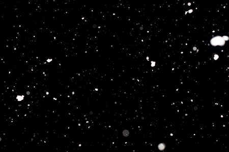Snowstorm texture. Bokeh lights on black background, shot of flying snowflakes in the airの写真素材
