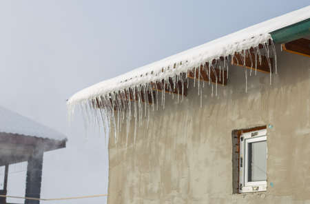 Icicles on vintage roof closeup. Winter weather concept. Froze and ice background. Christmas weather concept. Snow and icicle. Melting icicles. Long sharp icicles. Frozen water. Cold weather conceptの写真素材