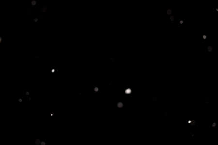 Snowstorm texture. Bokeh lights on black background, shot of flying snowflakes in the airの写真素材