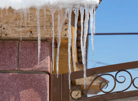 Icicles on vintage roof closeup. Winter weather concept. Froze and ice background. Christmas weather concept. Snow and icicle. Melting icicles. Long sharp icicles. Frozen water. Cold weather conceptの写真素材