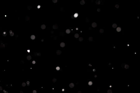 Snowstorm texture. Bokeh lights on black background, shot of flying snowflakes in the airの写真素材