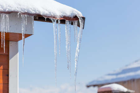 Icicle melts with falling drops on a background of bright blue skyの写真素材