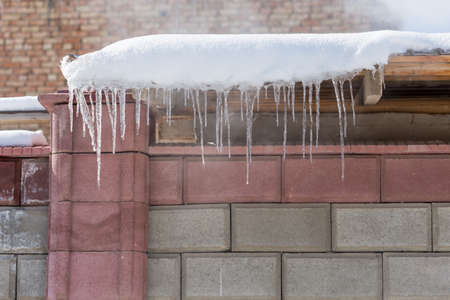 Icicles on vintage roof closeup. Winter weather concept. Froze and ice background. Christmas weather concept. Snow and icicle. Melting icicles. Long sharp icicles. Frozen water. Cold weather conceptの写真素材