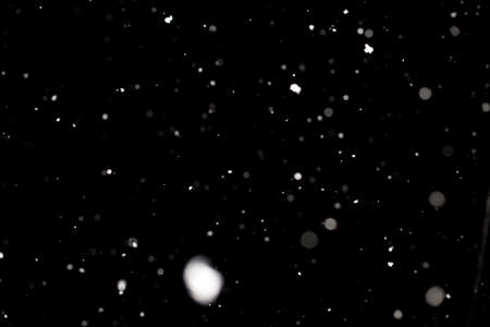 Snowstorm texture. Bokeh lights on black background, shot of flying snowflakes in the airの写真素材