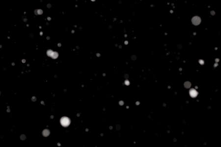 Snowstorm texture. Bokeh lights on black background, shot of flying snowflakes in the airの写真素材