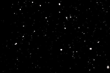 Snowstorm texture. Bokeh lights on black background, shot of flying snowflakes in the airの写真素材