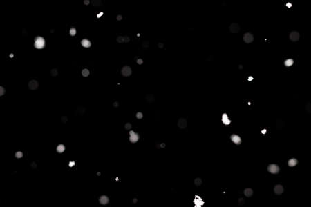 Snowstorm texture. Bokeh lights on black background, shot of flying snowflakes in the airの写真素材