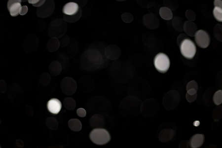 Snowstorm texture. Bokeh lights on black background, shot of flying snowflakes in the airの写真素材