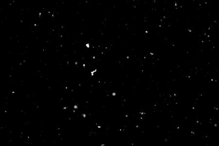Snowstorm texture. Bokeh lights on black background, shot of flying snowflakes in the airの写真素材