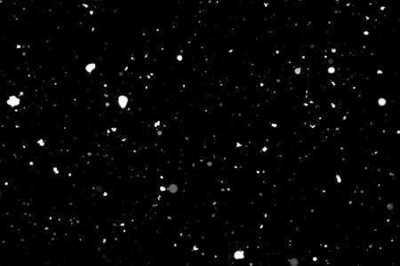 Snowstorm texture. Bokeh lights on black background, shot of flying snowflakes in the airの写真素材