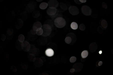 Snowstorm texture. Bokeh lights on black background, shot of flying snowflakes in the airの写真素材