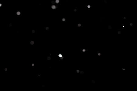 Snowstorm texture. Bokeh lights on black background, shot of flying snowflakes in the airの写真素材