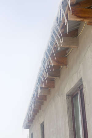 Icicles on vintage roof closeup. Winter weather concept. Froze and ice background. Christmas weather concept. Snow and icicle. Melting icicles. Long sharp icicles. Frozen water. Cold weather conceptの写真素材