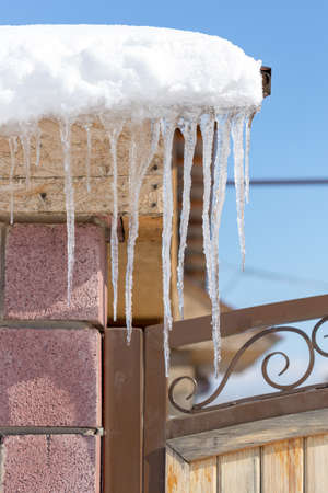 Icicles on vintage roof closeup. Winter weather concept. Froze and ice background. Christmas weather concept. Snow and icicle. Melting icicles. Long sharp icicles. Frozen water. Cold weather conceptの写真素材