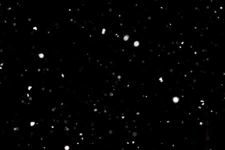 Snowstorm texture. Bokeh lights on black background, shot of flying snowflakes in the airの写真素材