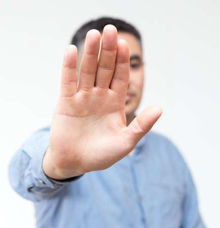 Portrait of a man in a blue shirt prohibits to shoot himself in the camera on a white background