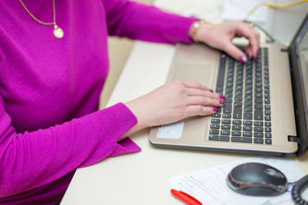 Close up of woman hands working with laptop in officeの写真素材