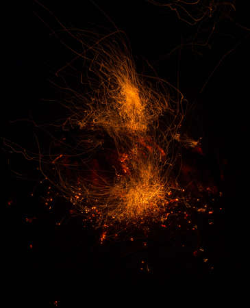 Burning fire in the night. Flame and fire sparkles on a dark abstract background. Hellish element of fire. Fuel, power and energyの写真素材