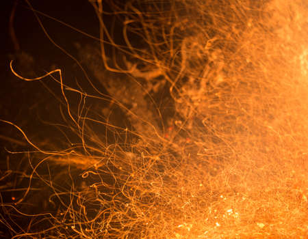 Burning fire in the night. Flame and fire sparkles on a dark abstract background. Hellish element of fire. Fuel, power and energyの写真素材
