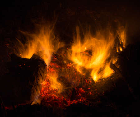Burning fire in the night. Flame and fire sparkles on a dark abstract background. Hellish element of fire. Fuel, power and energyの写真素材