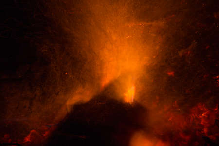 Burning fire in the night. Flame and fire sparkles on a dark abstract background. Hellish element of fire. Fuel, power and energyの写真素材