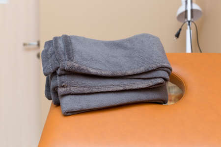 Spa treatment room with a row of clean brown beds with black towels in the room.の写真素材