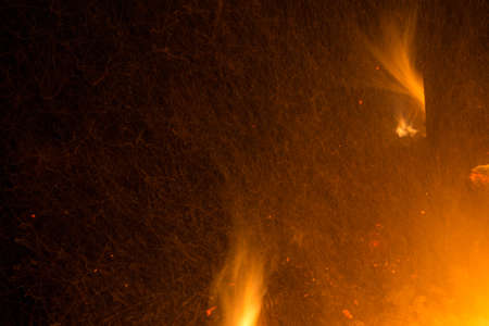 Burning fire in the night. Flame and fire sparkles on a dark abstract background. Hellish element of fire. Fuel, power and energyの写真素材