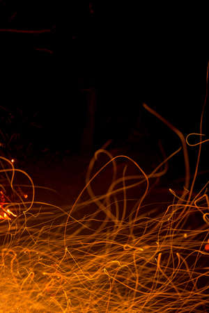 Burning fire in the night. Flame and fire sparkles on a dark abstract background. Hellish element of fire. Fuel, power and energyの写真素材