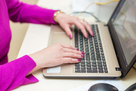 Close up of woman hands working with laptop in officeの写真素材