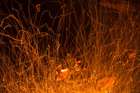 Burning fire in the night. Flame and fire sparkles on a dark abstract background. Hellish element of fire. Fuel, power and energyの写真素材