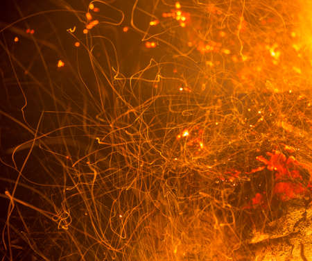 Burning fire in the night. Flame and fire sparkles on a dark abstract background. Hellish element of fire. Fuel, power and energyの写真素材