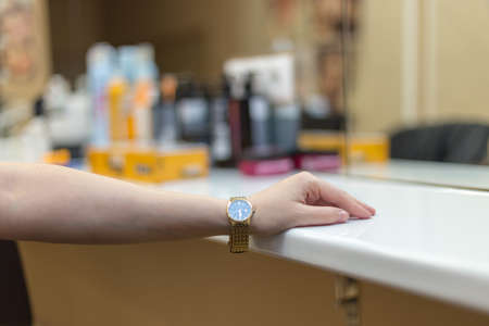 Female hand on the table in the beauty salon and on it is a gold watch.の写真素材