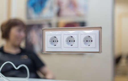 A set of three outlets installed on the mirror in the beauty salon. For the master it is convenient to work. In the background a blurred silhouette of a girlの写真素材