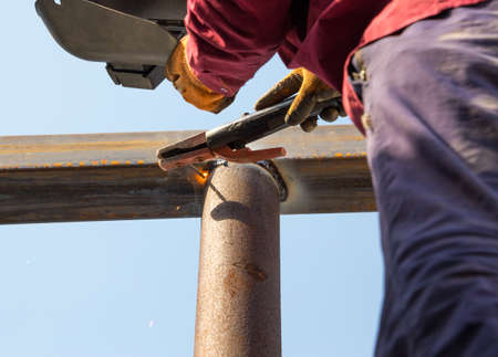 close-up of arc welding in the workplace, fastening the steel canopy frame with protective helmets from flying sparks. Gloves in handの写真素材