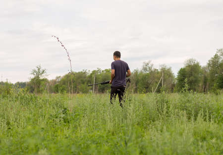 Young man shoots air rifle in nature
