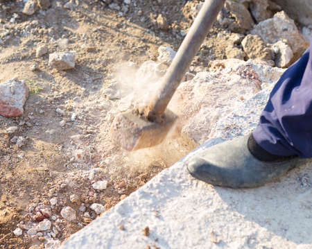 man smashes concrete with heavy sledgehammer