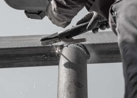 close-up of arc welding in the workplace, fastening the steel canopy frame with protective helmets...