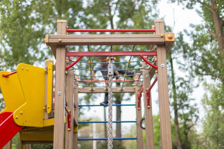 brave boy playing on the playground and going down with ropes downの写真素材