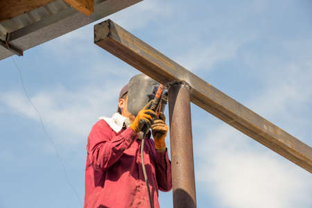 close-up of arc welding in the workplace, fastening the steel canopy frame with protective helmets...