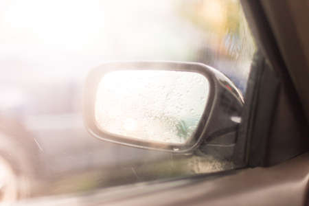 Car side mirror glass with water droplets from rain - driver's side rear view on rainy dayの写真素材