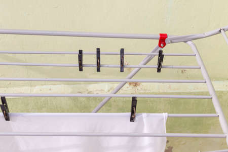 A rack dryer stands outside on a sunny day to dry white clothes. Foldable clothes dryer.の写真素材