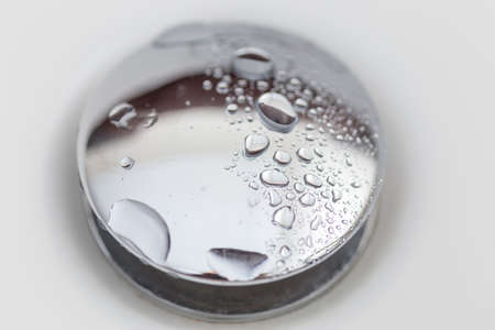 background, a drop of water on a shiny drain in the bathroom or on the sink close-upの写真素材