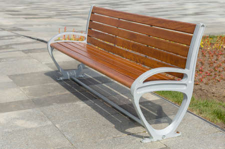Bench in the summer square, an empty bench for rest. Empty wooden bench in a city park. Wooden bench in the park on a beautiful summer dayの写真素材