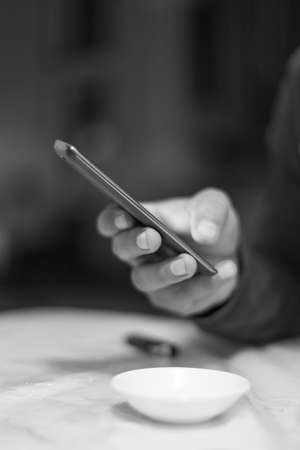 A man holding the hands of a mobile phone, is looking for online work on the Internet or social connection with the application for digital devices with 5G technology in an internal coffee shop.の写真素材
