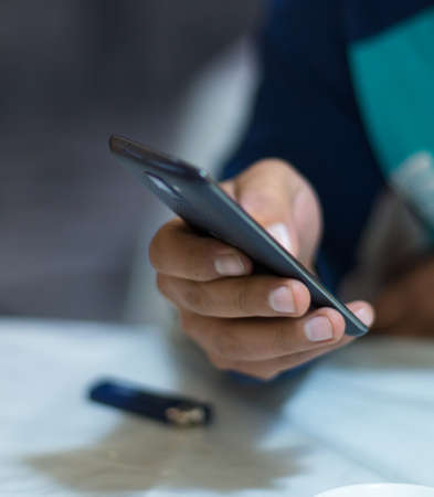 A man holding the hands of a mobile phone, is looking for online work on the Internet or social connection with the application for digital devices with 5G technology in an internal coffee shop.の写真素材