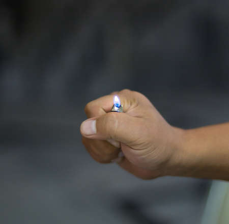 Hand of burning gas lighters on a dark background, portable device used to create a flameの写真素材