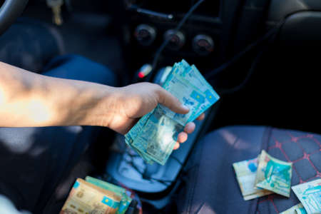 man counts Kazakh money in a car seatの写真素材