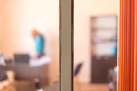 images from an office street, through a window with an orange curtain, silhouette of a man on a blurred backgroundの写真素材