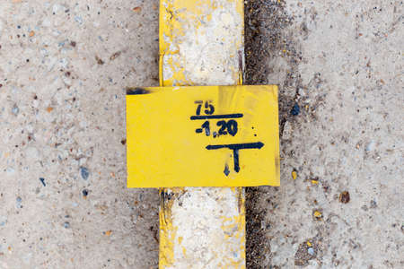 warning telephone yellow plate on a yellow concrete pillar lies on the groundの写真素材